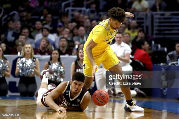 Tyler Davis of the Texas A&M Aggies and Isaiah Livers of the Michigan Wolverines go for a loose ball in the second half in the 2018 NCAA Men's...