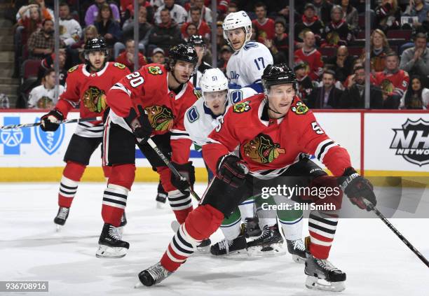 Connor Murphy of the Chicago Blackhawks reaches for the puck in front of Troy Stecher of the Vancouver Canucks and Brandon Saad in the first period...