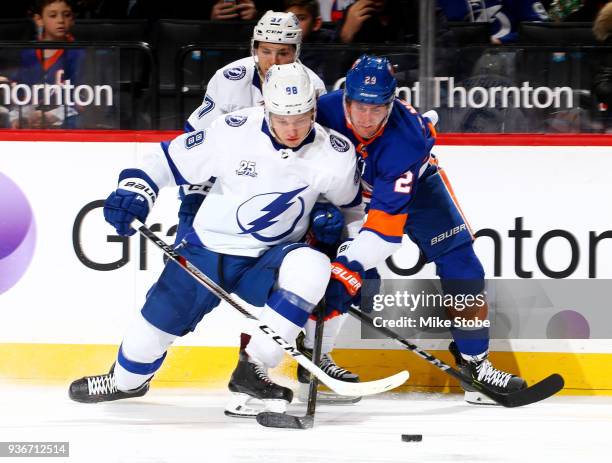 Brock Nelson of the New York Islanders battles for control of the puck with Mikhail Sergachev and Yanni Gourde of the Tampa Bay Lightning during the...