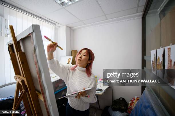 In this picture taken on March 12 mural artist Jackie Chung who works under the name "Pinkhead", paints during an interview with AFP in a subdivided...