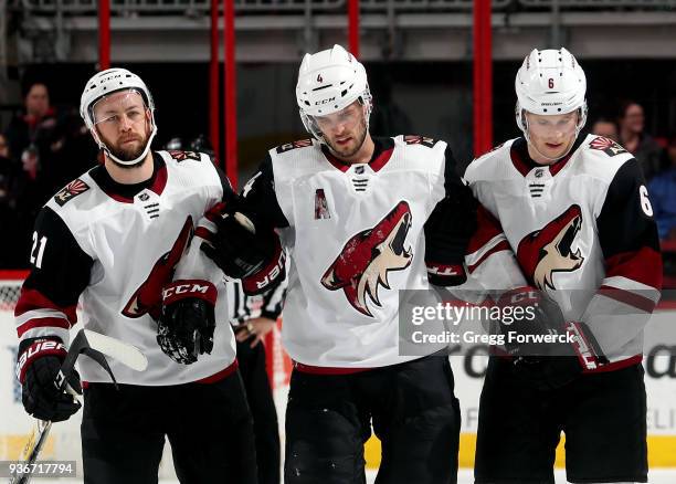 Niklas Hjalmarsson of the Arizona Coyotes is helped off the ice by teammates Derek Stepan and Jakob Chychrun during an NHL game against the Carolina...