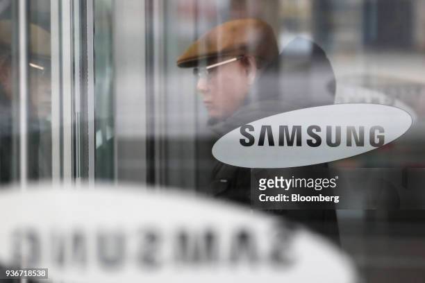 Man walks past Samsung Electronics Co. Logos displayed on glass doors at the company's Seocho office building in Seoul, South Korea, on Friday, March...