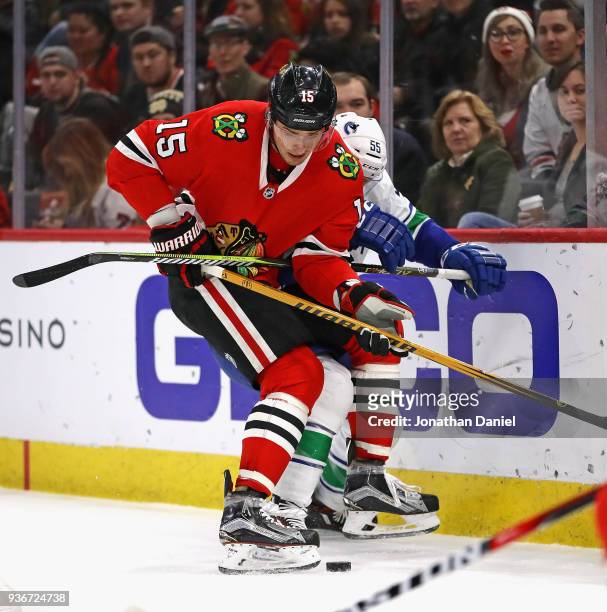 Artem Anisimov of the Chicago Blackhawks and Alex Biega of the Vancouver Canucks battle for the puck behind the net at the United Center on March 22,...
