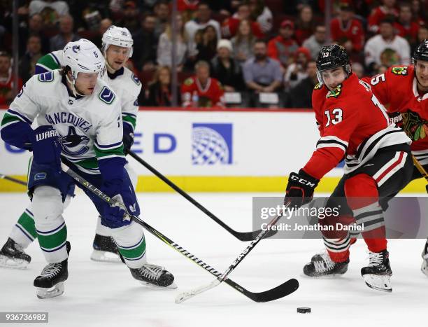 Derrick Pouliot of the Vancouver Canucks knocks the puck away from Tomas Jurco of the Chicago Blackhawks at the United Center on March 22, 2018 in...