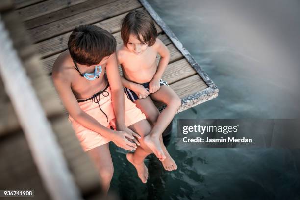 two young boys sitting on jetty - dip toe stock pictures, royalty-free photos & images