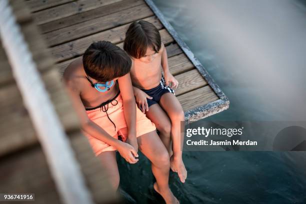 two young boys sitting on jetty - dip toe stock pictures, royalty-free photos & images