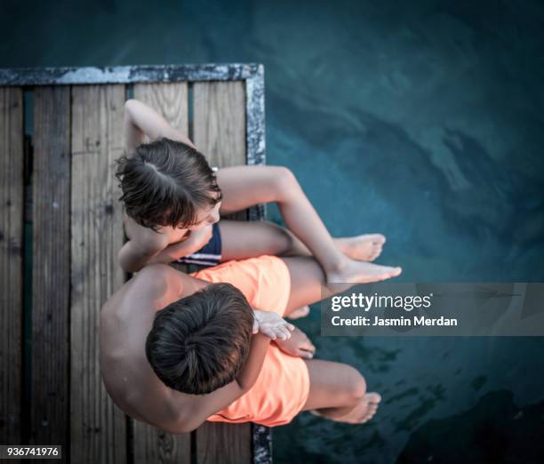 two young boys sitting on jetty - dip toe stock pictures, royalty-free photos & images