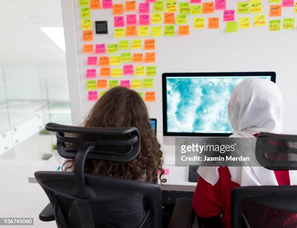 two muslim girls working on computer - jalabib stock pictures, royalty-free photos & images