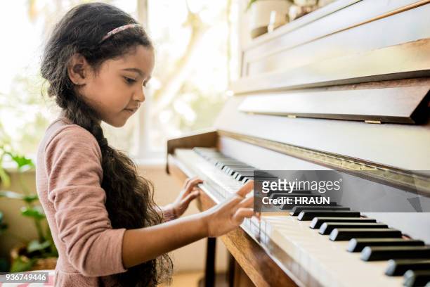 linda chica tocando el piano en casa - eficacia fotografías e imágenes de stock