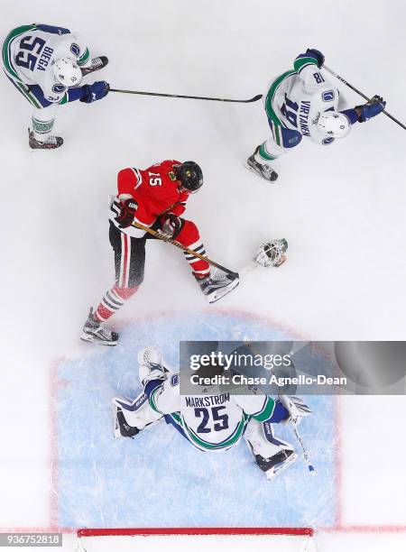 Artem Anisimov of the Chicago Blackhawks falls in between Alex Biega, cJake Virtanen and goalie Jacob Markstrom of the Vancouver Canucks in the third...