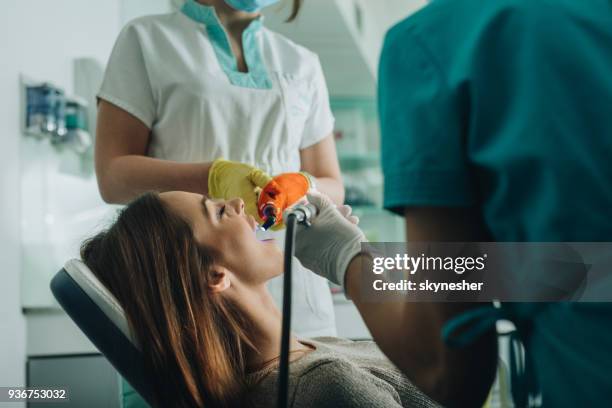 vrouw tandheelkundige behandeling met ultraviolet verlichting apparatuur. - dental explorer stockfoto's en -beelden