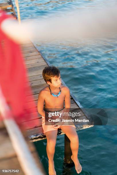 young boy sitting on jetty - dip toe stock pictures, royalty-free photos & images