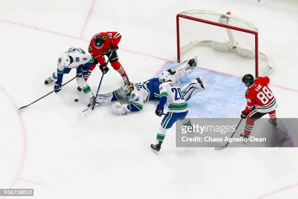Christopher Tanev of the Vancouver Canucks and John Hayden of the Chicago Blackhawks work to get the puck in front of goalie Jacob Markstrom at the...