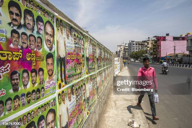 Pedestrian walks past election campaign posters for the Janata Dal Party in Bengaluru, Karnataka, India, on Wednesday, March 14, 2018. Prime Minister...