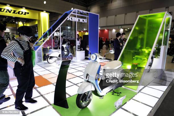 An attendee looks at a Kwang Yang Motor Co. Ionex electric scooter on display at the Tokyo Motorcycle Show in Tokyo, Japan, on Friday, March 23,...