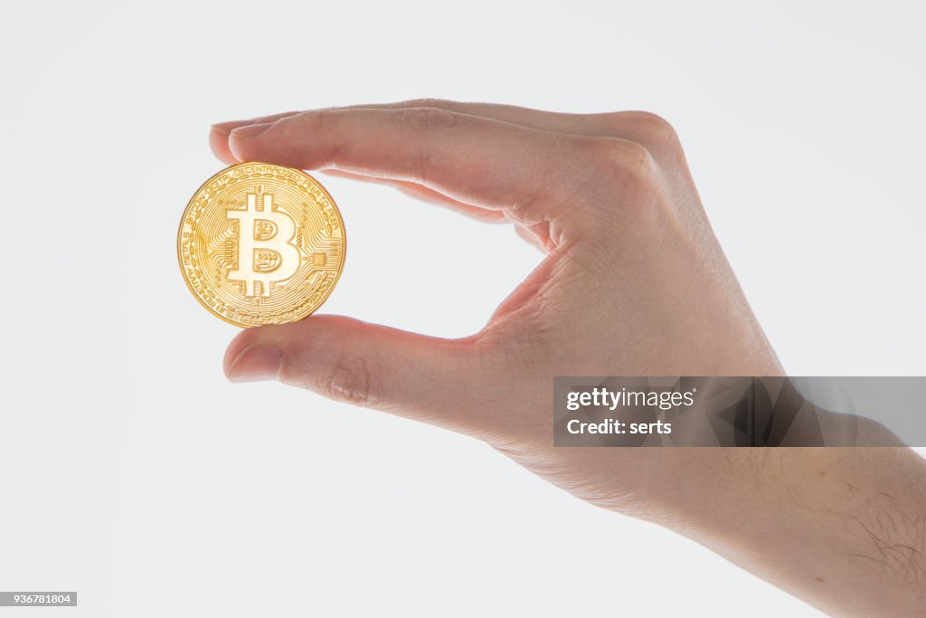 Hand holding golden bitcoin coin on white background