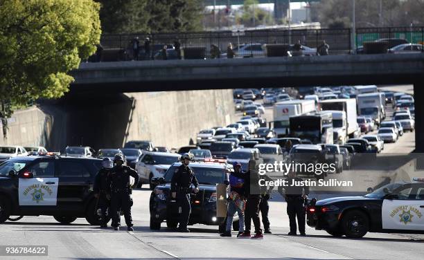 California Highway Patrol officers confront a Black Lives Matter protester as he marches Interstate 5 during a demonstration on March 22, 2018 in...