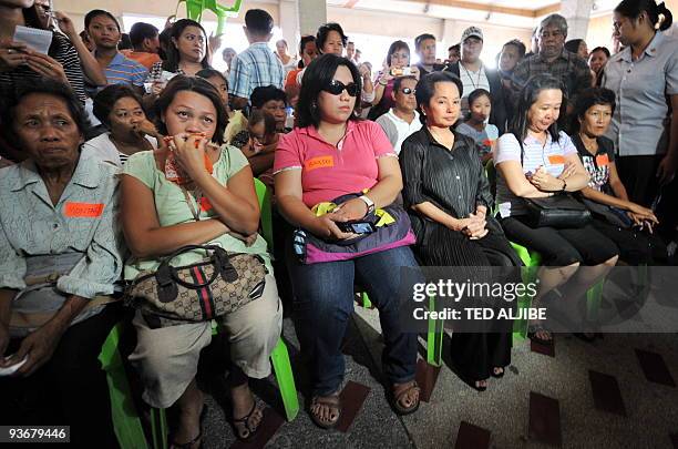 Philippine President Gloria Arroyo sits next to relatives of slain journalists during a visit at the wake in General Santos City, south Cotabato...