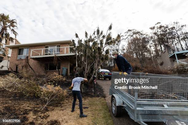 Lean Tong and Jack Morris clean up at their family home, which narrowly escaped the devasation in much of their street on March 23, 2018 in Tathra,...