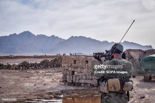 Afghan Commando scanning the area through the scope of his M16 assault rifle outside the remains of an Afghan National Defence and Security Forces...