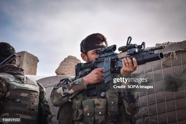 Afghan Commando peering through the scope of his M16 assault rifle, Farahrud Bazaar, Bolo Bluk district, Farah province. Afghanistans elite military...