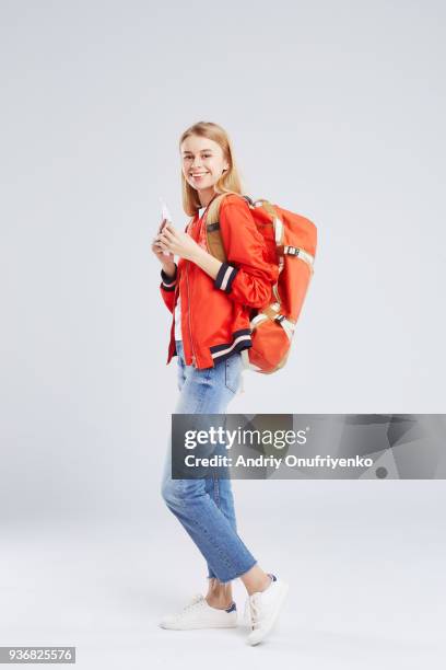 studio portrait of blond woman wearing backpack - backpacker woman stock-fotos und bilder