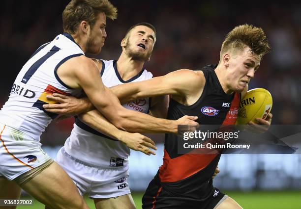 Joshua Begley of the Bombers is tackled by Paul Seedsman of the Crows during the round one AFL match between the Essendon Bombers and the Adelaide...