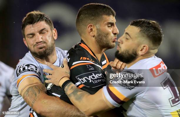 Alex Twal of the Tigers is tackled by Matt Gillett and Jack Bird of the Broncos during the round three NRL match between the Wests Tigers and the...