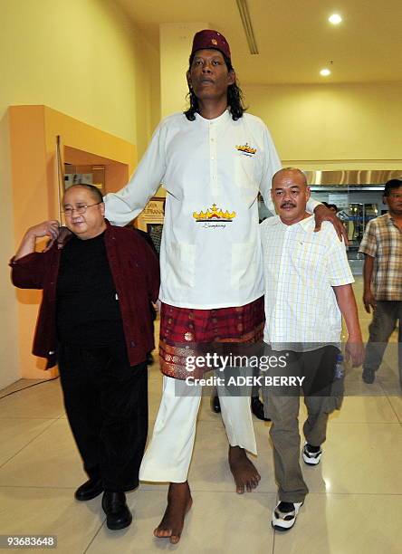 Indonesian man Suparwono walks helped by Jaya Suprana from the Indonesian Museum of Records and a relative during an awards ceremony in Jakarta on...