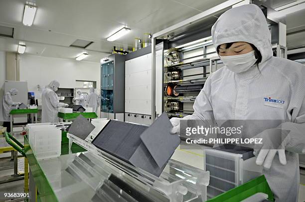 Climate-warming-China-solar,FOCUS by D'Arcy Doran This picture taken on November 28, 2009 shows a masked worker in a lab coat sorting silicon wafers...