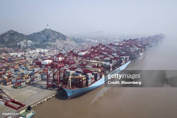 An A.P. Moller-Maersk A/S container ship and a Hapag-Lloyd AG container ship are docked as shipping containers stand in a terminal at the Yangshan...