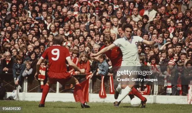 West Ham United player Trevor Brooking in action against Steve Heighway and Joey Jones of Liverpool as the crowd look on during a First Division...