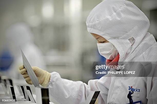 Climate-warming-China-solar,FOCUS by D'Arcy Doran This picture taken on November 28, 2009 shows a masked worker in a lab coat sorting silicon wafers...