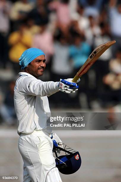 Indian cricketer Virendra Sehwag raises his bat after scoring a double century on the second day of the third test between India and Sri Lanka in...