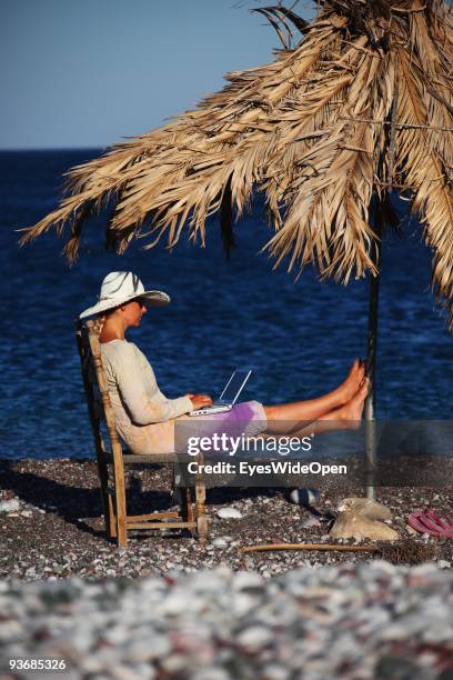 Woman on a beach working with a notebook near Lindos on July 16, 2009 in Rhodes, Greece. Rhodes is the largest of the Greek Dodecanes Islands.