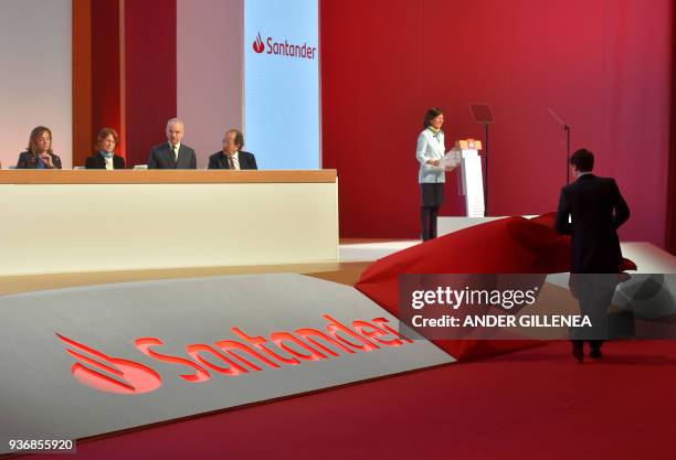 Man uinveils the new logo of Spanish Santander Bank next to Executive Chairman Ana Botin during the bank's general shareholders meeting in Santander,...