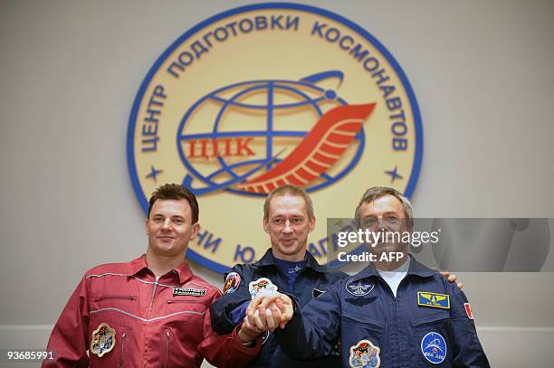 Russian cosmonaut Roman Romanenko , European Space Agency astronaut Frank de Winne of Belgium and Canadian astronaut Robert Thirsk clasp hands during...