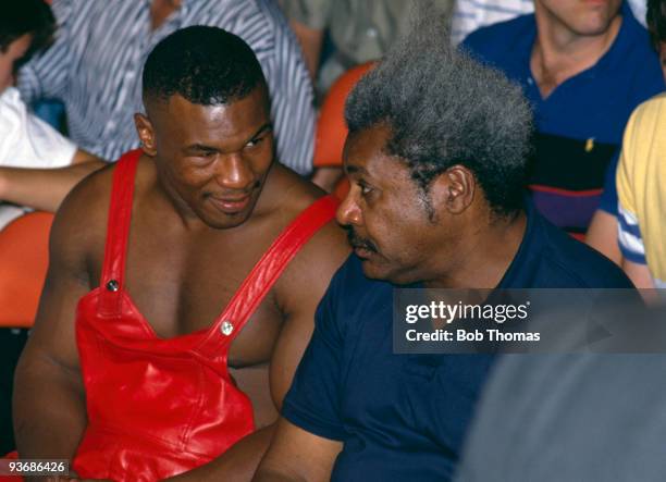 Amercian heavyweight boxer Mike Tyson sitting with promoter Don King watching Dennis Andries in action against Jeff Harding at the Convention Centre...
