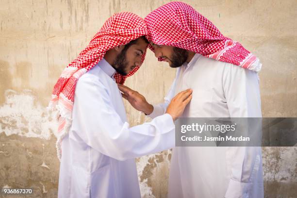 two young arabian man touching each other - ghoutra stock pictures, royalty-free photos & images