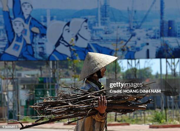 Vietnam-energy-oil-resources-development, by Peter Stebbings A villager collects bushwood for cooking walking past a poster featuring the newly built...