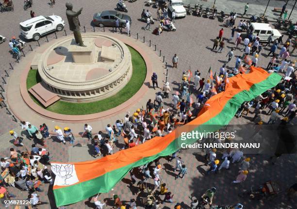Members of the Bharatiya Janata Party carry a BJP giant flag during a march to pay tribute to Indian socialist revolutionary Bhagat Singh near...