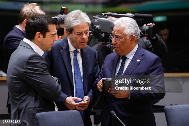 Antonio Costa, Portugal's prime minister, right, holds a smartphone as he speaks with Paolo Gentiloni, Italy's prime minister, center, and Alexis...