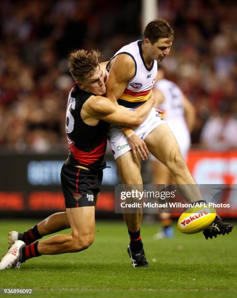 Jake Kelly of the Crows is tackled by Josh Begley of the Bombers during the 2018 AFL round 01 match between the Essendon Bombers and the Adelaide...