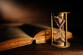 old hourglass and ancient book