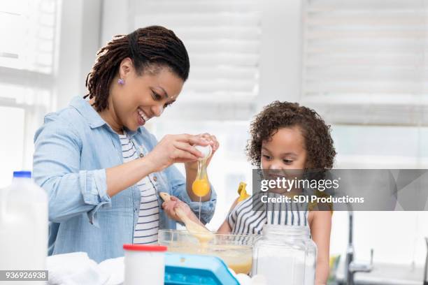 little girl helps mom bake a cake - crack spoon stock pictures, royalty-free photos & images