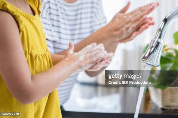 moeder toont dochter juiste manier om handen te wassen - child washing hands stockfoto's en -beelden