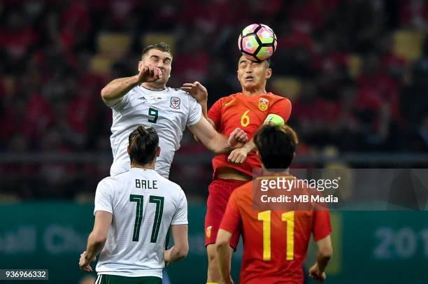 Feng Xiaoting, top, of Chinese national men's football team heads the ball to make a pass against Sam Vokes of Wales national football team in the...