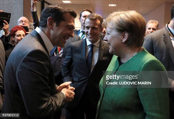 Greek Prime minister Alexis Tsipras, French president Emmanuel Macron and German chancellor Angela Merkel smile as they talk in a corridor at the end...