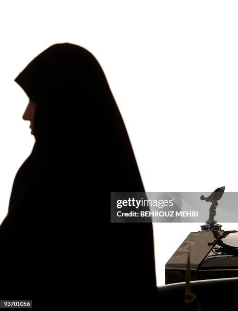 An Iranian woman walks past a Rolls-Royce Phantom VI during a classic cars show at Niavaran palace in Teran on July 20, 2009. About 60 classic cars...