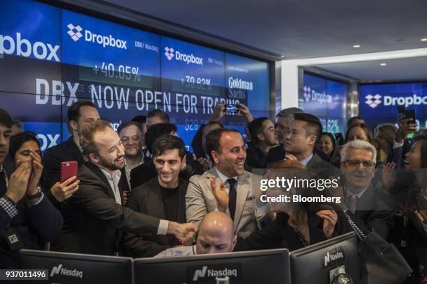 Drew Houston, chief executive officer and co-founder of Dropbox Inc., second left, and Arash Ferdowsi, co-founder of Dropbox Inc., third left, react...